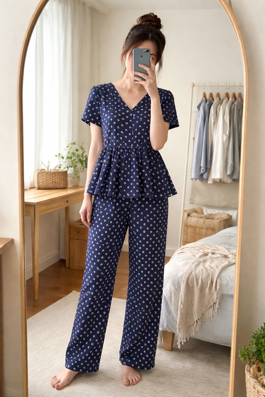 Woman wearing Blush Whispers navy blue peplum night suit with minimal prints and full-length pants, taking a mirror selfie in a cozy bedroom.
