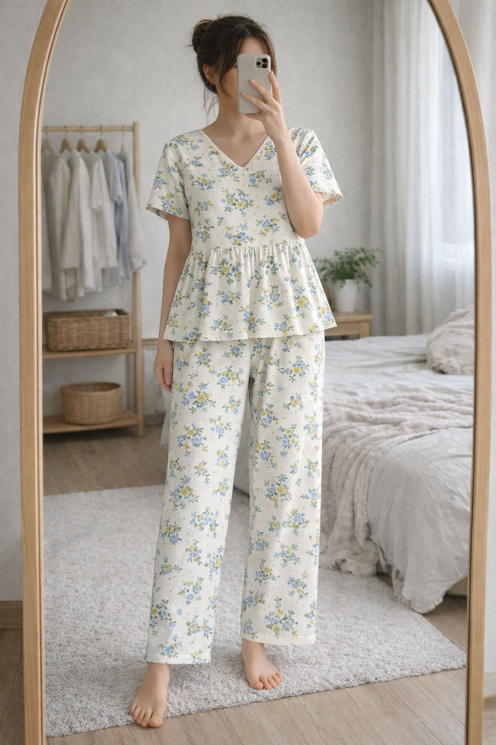 Woman wearing Blush Whispers cream peplum night suit with blue floral prints and full-length pants, taking a mirror selfie in a cozy bedroom.